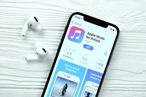 KHARKOV, UKRAINE - MARCH 5, 2021 Apple music for artists icon and application from App store on iPhone 12 pro display screen with airpods pro on white table photo
