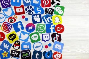 KHARKOV, UKRAINE - DECEMBER 26, 2020 Paper logos of most popular social networks and mobile messengers on wooden background. Facebook instagram youtube twitter tiktok twitch reddit etc. photo