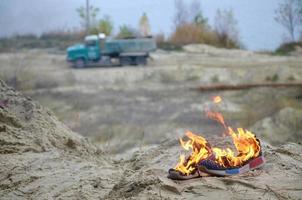 Burning sports sneakers or gym shoes on fire stand on sandy beach coast. Athlete burned out. Physical exertion during training concept photo