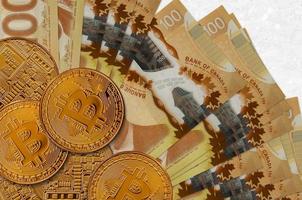 Billetes de 100 dólares canadienses y bitcoins dorados. concepto de inversión en criptomonedas. criptominería o comercio