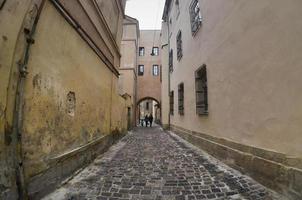 Narrow street with a path of paving stones. Passage between the old historical high-rise buildings in Lviv, Ukraine
