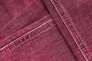 Detailed abstract texture of dark blue denim cloth. Background image of old used denim trousers fabric Image toned in Viva Magenta, color of the 2023 year photo