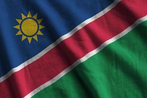 Namibia flag with big folds waving close up under the studio light indoors. The official symbols and colors in banner photo