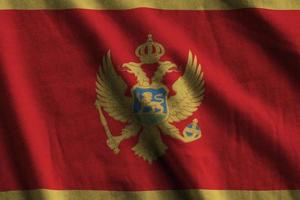 Montenegro flag with big folds waving close up under the studio light indoors. The official symbols and colors in banner photo