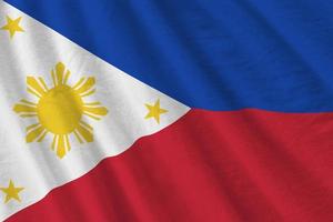 Philippines flag with big folds waving close up under the studio light indoors. The official symbols and colors in banner photo