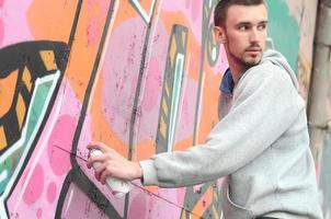 A young graffiti artist looks around while drawing. Vandal tries photo