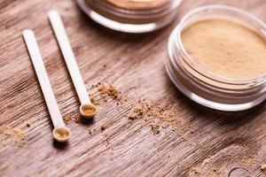 Mineral powder of different colors with a spoon dispenser for make-up on wooden background photo