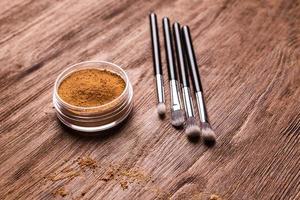 base de polvo mineral con pinceles sobre un fondo de madera. productos de belleza ecológicos y orgánicos foto