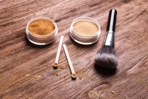 polvo mineral de diferentes colores con un dispensador de cuchara para maquillaje sobre fondo de madera foto