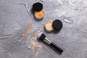 polvo mineral de diferentes colores con pinceles para maquillaje sobre fondo de madera. foto