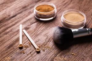 polvo mineral de diferentes colores con un dispensador de cuchara para maquillaje sobre fondo de madera foto