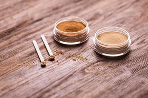 polvo mineral de diferentes colores con un dispensador de cuchara para maquillaje sobre fondo de madera foto