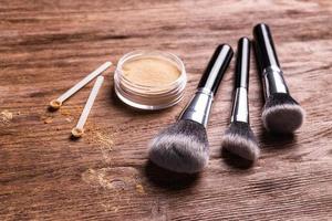 polvo mineral de diferentes colores con un dispensador de cuchara para maquillaje sobre fondo de madera foto