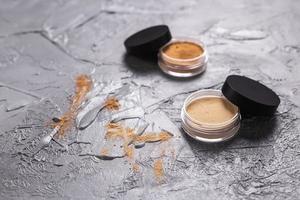 polvo mineral de diferentes colores con pinceles para maquillaje sobre fondo de madera. foto