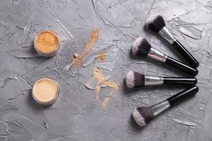 polvo mineral de diferentes colores con pinceles para maquillaje sobre fondo de madera, vista superior foto
