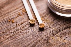 Mineral powder of different colors with a spoon dispenser for make-up on wooden background photo