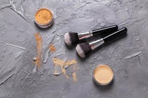 polvo mineral de diferentes colores con pinceles para maquillaje sobre fondo de madera, vista superior foto