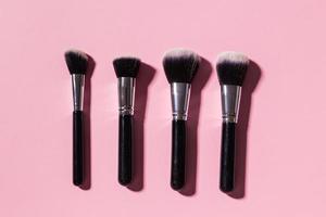 Various make-up brushes on pink background, top view. Cosmetics and beauty concept. photo
