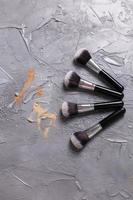 polvo mineral de diferentes colores con pinceles para maquillaje sobre fondo de madera, vista superior foto