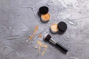 polvo mineral de diferentes colores con pinceles para maquillaje sobre fondo de madera. foto
