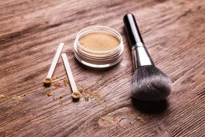 polvo mineral de diferentes colores con un dispensador de cuchara para maquillaje sobre fondo de madera foto