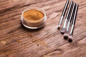 base de polvo mineral con pinceles sobre un fondo de madera. productos de belleza ecológicos y orgánicos foto