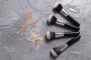 polvo mineral de diferentes colores con pinceles para maquillaje sobre fondo de madera, vista superior foto