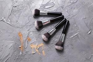 polvo mineral de diferentes colores con pinceles para maquillaje sobre fondo de madera, vista superior foto