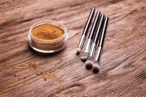 base de polvo mineral con pinceles sobre un fondo de madera. productos de belleza ecológicos y orgánicos foto