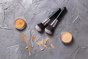 polvo mineral de diferentes colores con pinceles para maquillaje sobre fondo de madera, vista superior foto