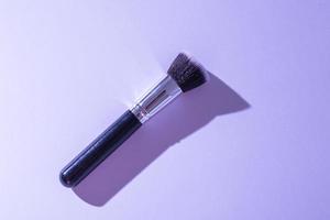 Make up brush on purple background, top view. photo