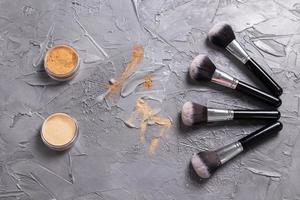 Mineral powder of different colors with a brushes for make-up on wooden background, top view photo