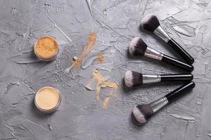 polvo mineral de diferentes colores con pinceles para maquillaje sobre fondo de madera, vista superior foto