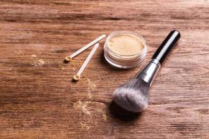 polvo mineral de diferentes colores con un dispensador de cuchara para maquillaje sobre fondo de madera foto