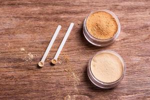 polvo mineral de diferentes colores con un dispensador de cuchara para maquillaje sobre fondo de madera foto