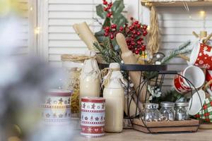 mesa en la cocina con botellas de leche, tazas y adornos navideños foto