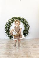 una niña sostiene una canasta con un conejo en el fondo de las decoraciones navideñas. símbolo del nuevo año 2023. foto