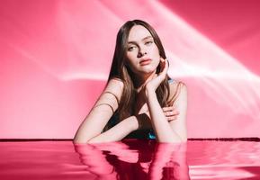 Beauty portrait with water of young woman fashion model with healthy dark long hair on magenta background photo