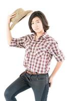 Young woman in a cowboy hat and plaid shirt with hand on her hat photo