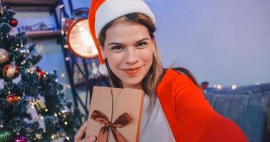 Beautiful young woman on video call invites her friends to Christmas party at her home. photo