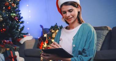 una hermosa mujer está usando una tableta para diseñar tarjetas navideñas para su familia y amigos. foto