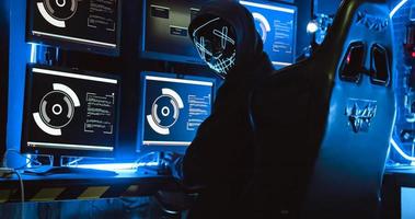 A hacker wearing a mask to cover his face is using computer to hack data to get ransom from victims. photo