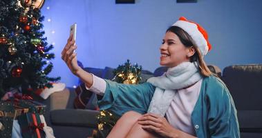 Beautiful young woman on video call invites her friends to Christmas party at her home. photo