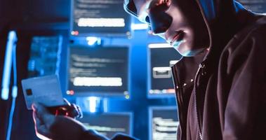 A hacker wearing a mask to cover his face is using computer to hack data to get ransom from victims. photo