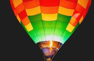 Close-up shot of bright and beautiful red, blue, yellow, and orange balloons rising in the night sky with a black background. photo