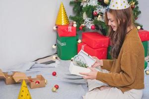 Merry Christmas and Happy Holidays Young woman with a beautiful face in a yellow shirt shows joy with gift boxes in a house with a Christmas tree decorated with Christmas tree.  Portrait before Xmas photo