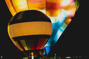 primer plano de globos rojos, azules, amarillos y naranjas brillantes y hermosos que se elevan en el cielo nocturno con un fondo negro. foto