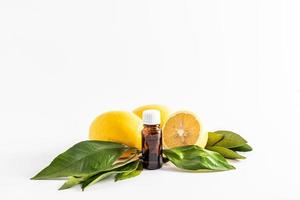 medical bottle made of dark glass with a white cork on the background of ripe lemons and leaves. lemon essential oil. vitamin C. Spa, aromatherapy. photo