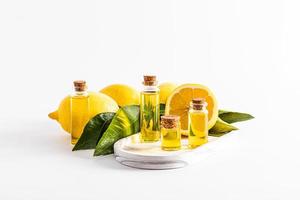 a set of glass bottles with a cork with organic lemon remedy, essence, oil on a white plaster tray among ripe fruits. white background. front view. photo