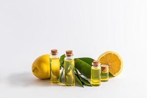 Various glass bottles with cork with organic lemon oil on a white background with ripe fruits. front view. natural care. photo